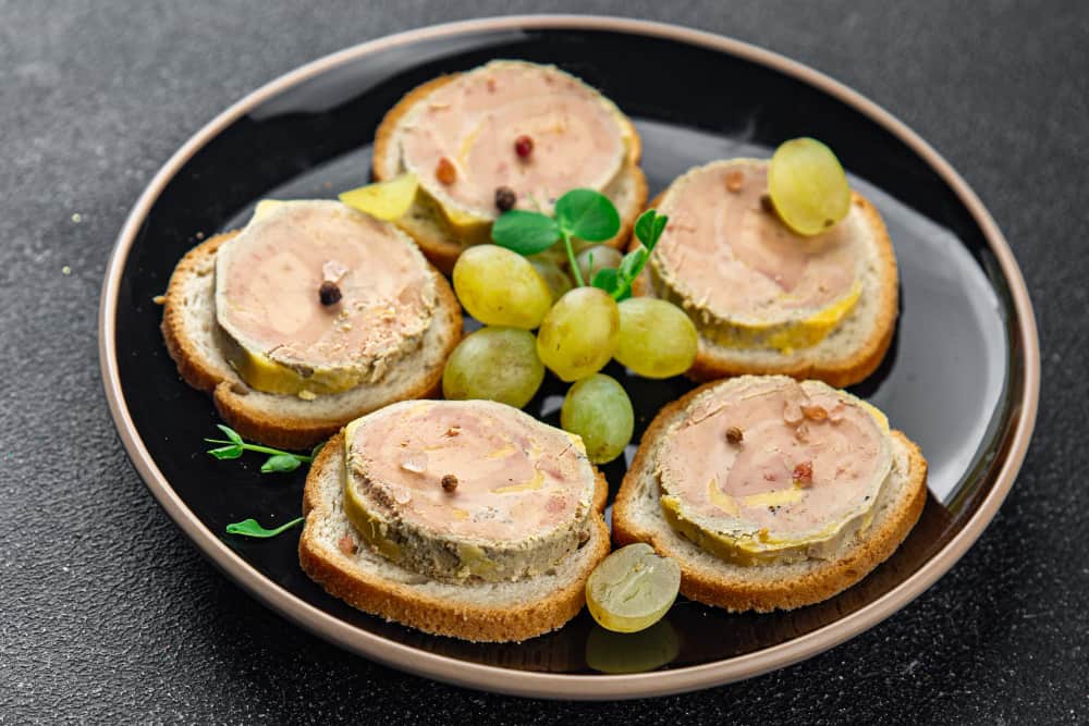 Médaillons de foie gras traiteur sur toasts de pain brioché avec grains de poivre et raisins frais