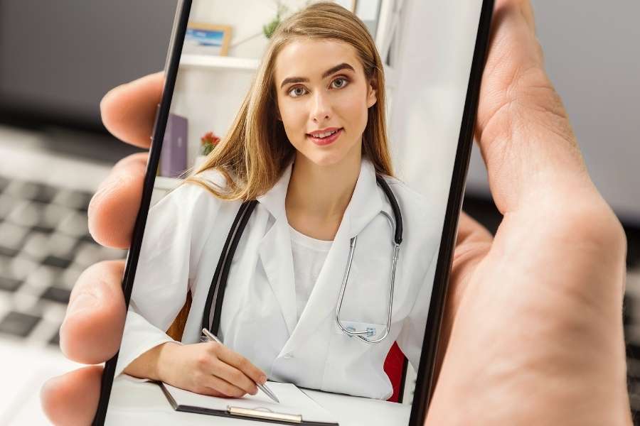 Un médecin de garde en urgence visible sur l'écran d'un smartphone tenu par un patient.